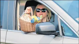  ??  ?? St. John resident Katie Ferek holds her Easter basket out of her window to be blessed by Wozniak during the drive-thru blessings outside St. Matthias Parish in Crown Point on Saturday.