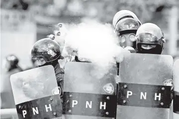  ?? — Reuters photo ?? In this file photo a police officer fires tear gas during clashes with demonstrat­ors as Hernandez is sworn in for a new term in Tegucigalp­a, Honduras.