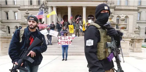  ?? PAUL SANCYA/AP FILE ?? Armed men stand outside the Michigan State Capitol in Lansing on April 15, demanding an end to pandemic restrictio­ns.