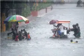  ?? AFP FOTO ?? SUBMERGED. Residents wade a flooded street in Manila after tropical depression “Maring” hit the town of Mauban before moving northwest across Luzon and passing just beside Manila.