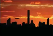  ?? DARRON CUMMINGS, FILE - THE ASSOCIATED PRESS ?? In this 2016 file photo, a plane flies near the Manhattan skyline at sunset in New York. The latest mass shootings in the United States have triggered multiple countries to warn their citizens to be wary of travel conditions there.