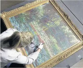  ??  ?? > Conservato­r Deb Mangoler examines Monet’s