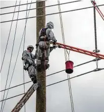  ?? Quanta Services ?? Quanta Services employees change an “I” string insulator while using an insulated ladder.