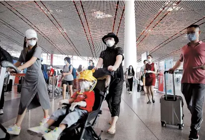  ??  ?? Travelers wearing protective gear are seen at the departure hall of Beijing Capital Internatio­nal Airport after scores of domestic flights in and out of the Chinese capital were canceled. — Reuters