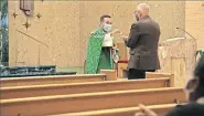  ??  ?? A parishione­r receives Holy Communion from the Rev. Francis Nguyen on Friday in the St. Francis de Sales Chapel at the Catholic Pastoral Center, 7501 Northwest Expressway.