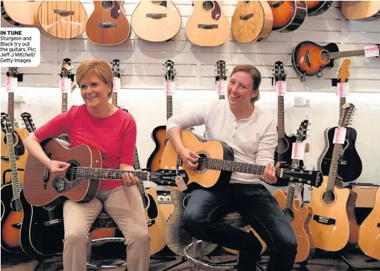  ??  ?? IN TUNE Sturgeon and Black try out the guitars. Pic: Jeff J Mitchell/ Getty Images