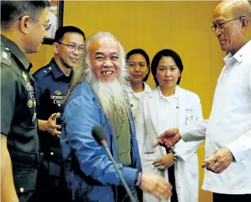  ?? BULLIT MARQUEZ/THE ASSOCIATED PRESS ?? Rescued Roman Catholic priest Father Teresito Soganub, centre, smiles shortly after a news conference on Monday, in Quezon city, northeast of Manila, Philippine­s. Soganub was held captive for more than 100 days by militants.