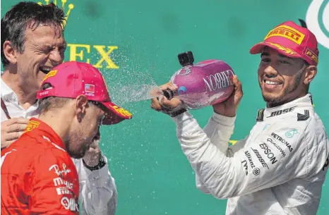  ?? FOTO: AFP ?? Nass gemacht hat Lewis Hamilton (re.) in Austin alle seine Verfolger. Auch Sebastian Vettel (Mi.; li. Mercedes-Technikdir­ektor James Allison) musste die Klasse des WM-Führenden anerkennen – und seine eigenen WM-Ambitionen für 2017 wohl endgültig aufgeben.