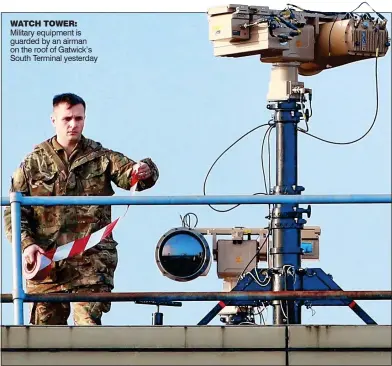  ??  ?? WATCH TOWER: Military equipment is guarded by an airman on the roof of Gatwick’s South Terminal yesterday
