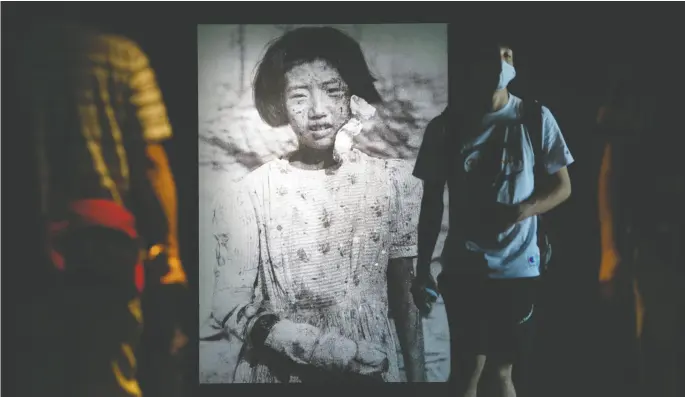  ?? Carl Court / Gett
y Images ?? People walk past a photograph of 10-year- old atomic-bomb survivor Yukiko Fuji — who went on to have two children but died of cancer at the age of 42 — as they
visit Hiroshima Peace Memorial Museum on Wednesday. Thursday marks the 75th anniversar­y of the atomic bombing of Hiroshima.