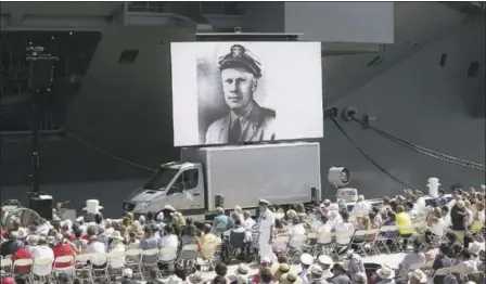  ?? PHOTOS BY STEVE EARLEY — THE ASSOCIATED PRESS ?? An image of President Ford as a naval officer is shown on a video screen on the pier during the commission­ing ceremony for the USS Gerald R. Ford at Norfolk Naval Station on Saturday in Virginia. President Donald Trump helped commission the newest Navy...