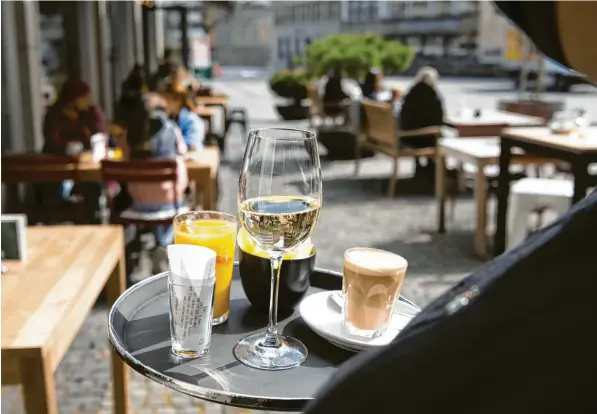  ?? Foto: Christian Beutler/Keystone, dpa ?? Das ist kein Archivfoto, sondern neuer Alltag in St. Gallen: Cappuccino, Wein und Orangensaf­t auf dem Tablett einer Kellnerin der Bar „Blumenmark­t“.