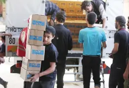  ??  ?? Syrians unload boxes of aid donated by UNHCR in the opposition-held and besieged town of Harasta, in the Eastern Ghouta region outside Damascus, on Monday. (AFP)