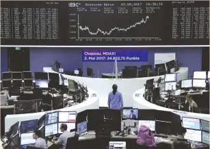  ?? (Reuters) ?? TRADERS WORK in front of the German share price index board at the stock exchange in Frankfurt yesterday.