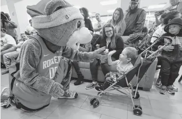  ?? Steve Gonzales / Staff photograph­er ?? Rockets mascot Clutch greets James Campos, 2, with a high-five during the team’s holiday party for children and families of Ronald McDonald House Houston’s flagship facility, Holcombe House, on Tuesday.