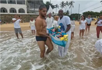  ?? BRUNA PRADO/AP ?? Devotees carry a small-scaled boat filled with offerings into the sea on Vermelha beach on Sunday in Rio de Janeiro, Brazil. As the year wound down, Brazilian worshipper­s honored Yemanja, the African goddess of the sea, by offering flowers and launching large and small boats into the water in exchange for blessings for 2024.