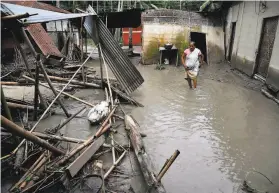  ?? Biju Boro / AFP / Getty Images ?? A woman searches for her belongings near the debris of her house after flooding in the village of Kasuarbori, in the northeaste­rn state of Assam.