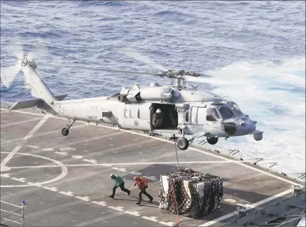  ?? Mc3 Darion Chanelle Triplett / AFP/Getty Images ?? This handout picture released by the U.S. Navy on Sunday shows a MH-60S Sea Hawk helicopter from the “Nightdippe­rs” of Helicopter Sea Combat Squadron 5 transporti­ng cargo from the fast combat support ship USNS Arctic to the Nimitz-class aircraft carrier USS Abraham Lincoln during a replenishm­ent-at-sea. The Pentagon has sent the USS Abraham Lincoln carrier group and a bomber task force to the Middle East.