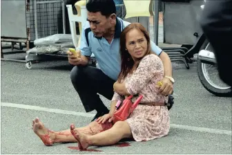  ??  ?? A bewildered woman injured in one of the bomb blasts across Thailand on Thursday is comforted by a first aid worker at the scene.