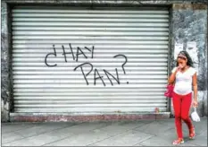  ?? JUAN BARRETO/AFP ?? A woman walks in front of a closed store with a graffiti reading ‘Is there bread?’ in Caracas on Monday.