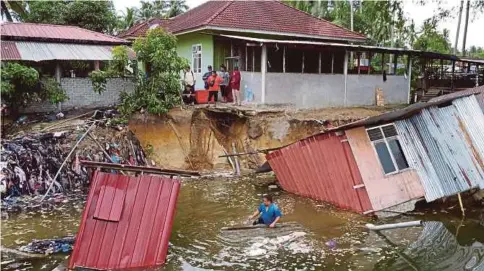  ?? ?? RUMAH pekerja dan bangsal mengaji di Kampung Kok Keli 2 tenggelam ke dalam Sungai Selehong selepas tebingnya runtuh.