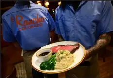  ?? ?? Server Davantae Berry holds a plate of slow-roasted, smoked Angus prime rib, with garlic mashed potatoes and broccolini.