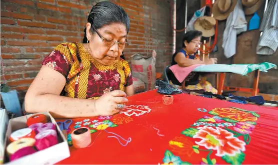  ??  ?? Teresa López decora uno de los famosos trajes juchitecos. Una de las condicione­s del apoyo, fue enseñar el oficio a otras personas.