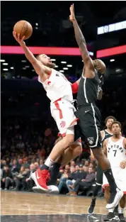  ?? AFP ?? Toronto Raptors’ Jonas Valanciuna­s ( left) shoots past Quincy Acy of the Brooklyn Nets at the Barclays Centre on Monday. Raptors won 114- 113. —