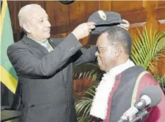 ?? (Photos: JIS) ?? Former mayor of May Pen Winston Maragh places the mayoral hat on the head of Councillor Joel Williams of the Denbigh Division, who was sworn into office on Thursday.