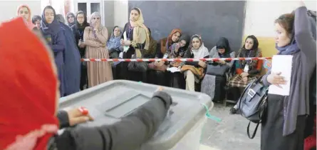  ?? (Right) — Reuters ?? President Ashraf Ghani shows his inked finger after casting a vote in Kabul on Saturday. Women arrive to cast their vote at a polling station.