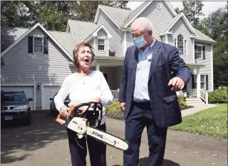  ?? Arnold Gold / Hearst Connecticu­t Media ?? Betty Perrone speaks with Eversource Executive Vice President Joseph Nolan while carrying her chainsaw in front of her home on Damascus Road in Branford on Aug. 28, while Gov. Ned Lamont viewed storm damage from tropical storm Isaias blocking the road and knocking down power lines.