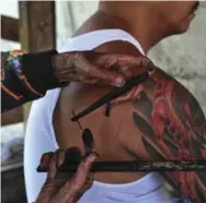  ??  ?? Fang-od tattoos a visitor in Buscalan, Philippine­s. Every morning, she mixes ink from pine soot and water.