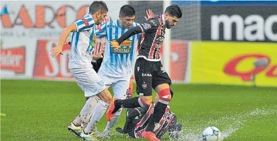  ?? MARCELO CARROLL ?? Se frenaba. Rodrigo Salinas intenta escapar de la marca de dos defensores jujeños. La cancha no soportó tanta agua.