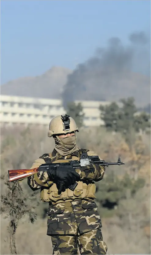  ?? WAKIL KOHSAR / AFP / GETTY IMAGES ?? An Afghan security officer stands guard as black smoke rises from the Interconti­nental Hotel following a weekend attack in Kabul.