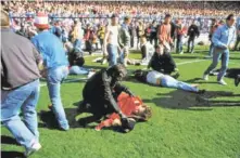  ?? AP FILE PHOTO ?? Police, stewards and supporters tend and care for wounded supporters April 15, 1989, on the pitch at Hillsborou­gh Stadium in Sheffield, England. Prosecutor­s charged a former senior police commander with manslaught­er Wednesday in the stadium disaster...