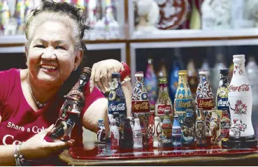  ??  ?? Consuelo "Ching" Santiago with her favorite Coca-Cola bottle from Argentina and the other special edition Coca-Cola bottles from other countries Photos bye JUN MENDOZA