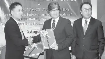  ??  ?? The exchange of the contract agreement documents between Merudi (left) and Medan. At right is Shamsuddin.