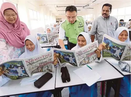  ?? PIC BY MOHD AZREN JAMALUDIN ?? SMK Medini principal Marsitah Mohd Noor (left) reading the ‘New Straits Times’ with students at the school’s Newspapers for English Language Enhancemen­t Workshop near Johor Baru recently. With them are Johor English Language Teaching Associatio­n president Vincent D’Silva (right) and the school’s Parent-Teacher Associatio­n chairman, Dr Othman Ibrahim.