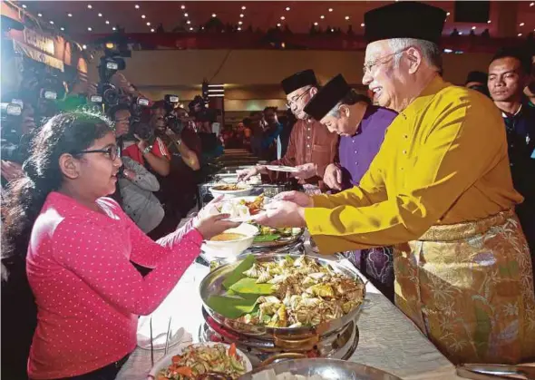  ?? PIC BY SAIRIEN NAFIS ?? Prime Minister Datuk Seri Najib Razak serving a young guest at the 2017 Umno Aidilfitri Open House at the Putra World Trade Centre yesterday. With him are Deputy Prime Minister Datuk Seri Dr Ahmad Zahid Hamidi and Defence Minister Datuk Seri...