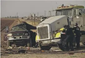  ?? PATRICK T. FALLON/AFP VIA GETTY IMAGES ?? Investigat­ors look over the wreckage of the crash between an SUV and a semi-truck full of gravel near Holtville, California, on Tuesday.