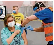  ?? CONTRIBUTE­D ?? Roberta Wells, a bus driver for Troy City Schools, gets her first dose of COVID-19 vaccine Friday as guidance counselor Paul Delwiche waits his turn. Troy schools partnered with Premier Health on the shots.