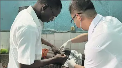  ?? THE 26TH CHINESE MEDICAL TEAM TO BENIN VIA XINHUA ?? Shi Baoyin (right), a member of the 26th Chinese medical team, guides a local doctor at the regional hospital of Natitingou in Atakora, Benin, in March.