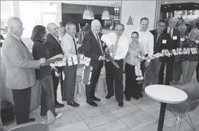  ??  ?? ABOVE: At center, Cumberland Mayor William Murray and Joe Napoli of Napoli Management, cut the ceremonial ribbon after renovation­s at the 1754 Mendon Road McDonald’s Restaurant, along with other employees and local officials.