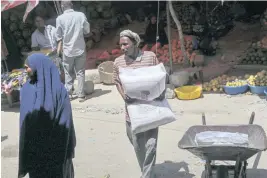  ?? FARAH ABDI WARSAMEH AP ?? A man carries a sack of wheat flour that was imported from Turkey at a market in Mogadishu, Somalia. Delegates from developing countries attending a pre-United Nations summit meeting hope awareness of the severe costs that global warming has for billions of people around the world will help narrow the gap that divides rich and poor nations.