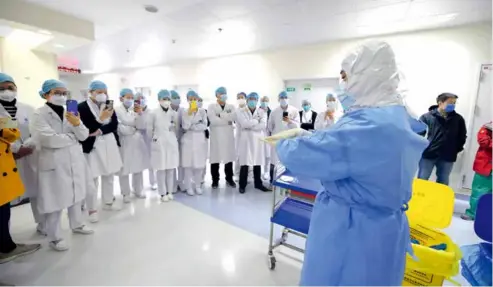  ?? 摄影 陶冉 ?? 2020年2月2日，武汉协和医院西院，来自北京援鄂医疗队的­队员对协和医院西院的­护理人员进行穿脱防护­服培训。