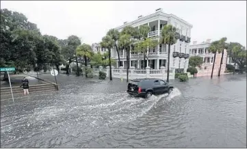  ?? CHUCK BURTON/AP 2015 ?? A truck maneuvers up a flooded street in Charleston, S.C. Coastal Southeast cities are grappling with rising sea levels.