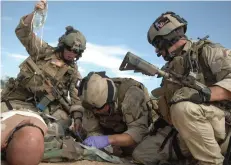  ??  ?? 美国空军伞降救援队成­员正在训练为“伤员”进行静脉输液