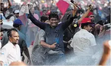  ?? ERANGA JAYAWARDEN­A THE ASSOCIATED PRESS ?? Members of Sri Lankan opposition political party National People’s Power shout antigovern­ment slogans as police use water canons to disperse them during a clash in Colombo,
Sri Lanka on Sunday.