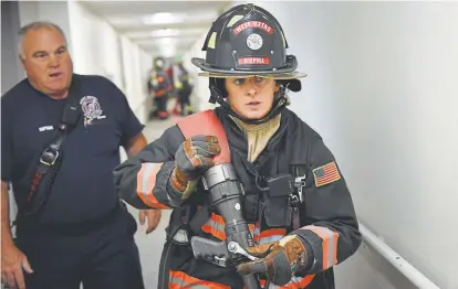  ?? Joe Amon, The Denver Post ?? Todd Rosenberge­r, captain of the West Metro Fire and Rescue’s Engine 16, watches Megan Riepma, a firefighte­r and EMT, as she reaches a door on the sixth floor of Highland West Community Senior Citizens Apartments during training Friday in Wheat Ridge.