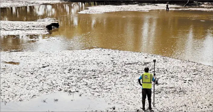  ?? CHARLIE RIEDEL/AP ?? U.S. Army Corps of Engineers worker Ron Allen uses a GPS tool Aug. 6 to survey the extent of damage where a levee failed along the Missouri River near Saline City, Mo.